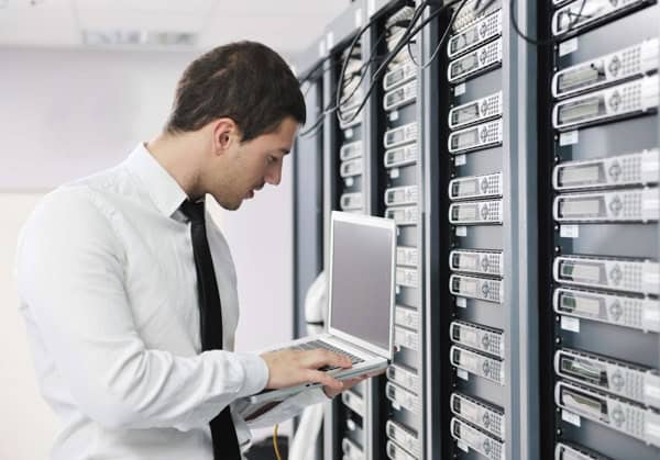 Man using a laptop in a data center server room