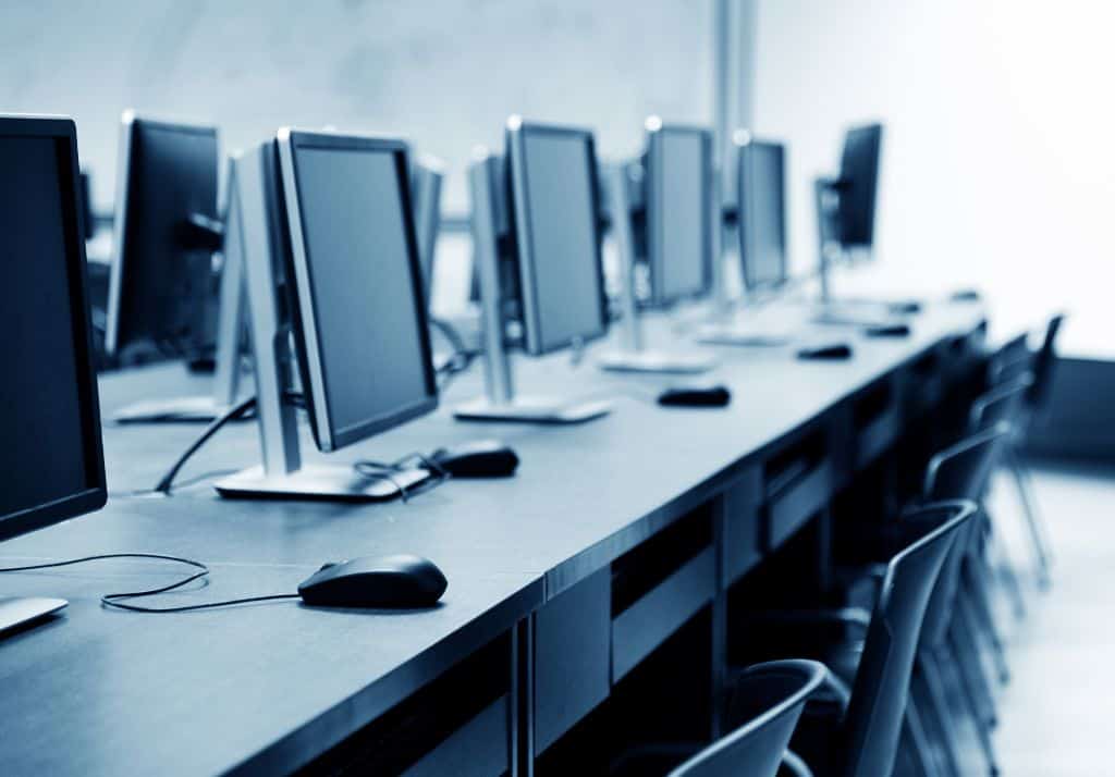 a row of computers on a desk in a corporate office