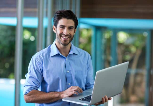a man in a blue shirt holding a laptop