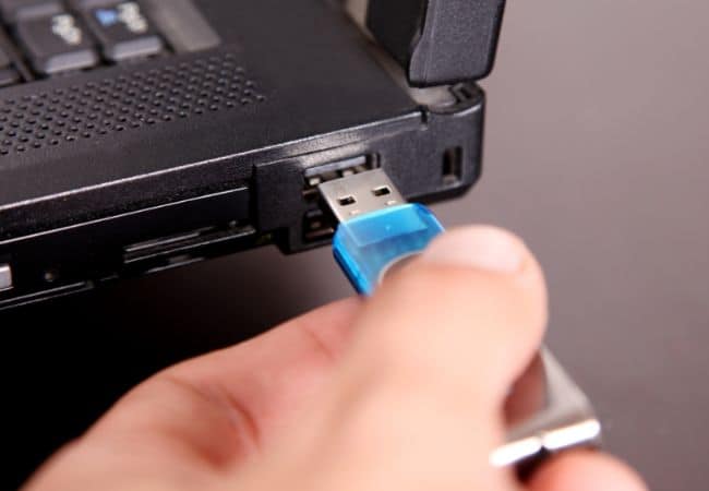 a hand is inserting a usb drive into a laptop